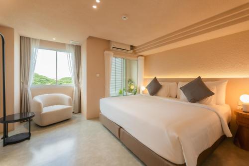 a bedroom with a large white bed and a chair at Mai Hotel Chiang Mai in Chiang Mai