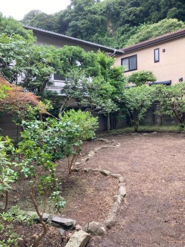 a garden in front of a house with trees at Guest House Sun-Sui 鎌倉 in Kamakura
