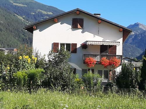 a white house with red flowers on a balcony at casa Pagnoncini in Prada
