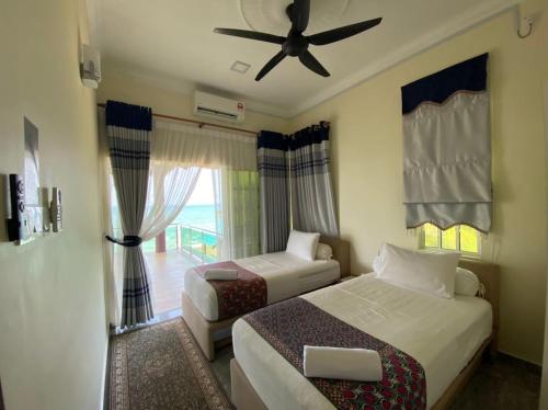 ein Hotelzimmer mit zwei Betten und einem Deckenventilator in der Unterkunft Che Beach House in Kampong Ru Sila