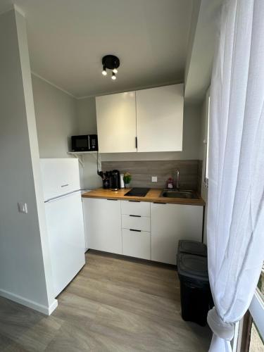 Elle comprend une petite cuisine avec des placards blancs et une fenêtre. dans l'établissement CENTRE CANNES - BEL APPARTEMENT LUMINEUx, à Cannes