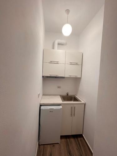 a small kitchen with white cabinets and a sink at Keivi Guesthouse in Sarandë