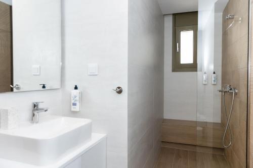 a white bathroom with a sink and a shower at SeaSide Village in Politiká