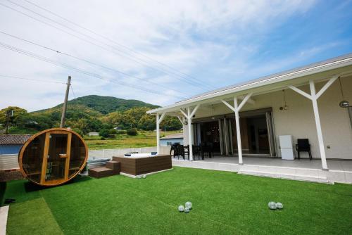 Una casa con césped y un círculo de madera encima. en dogs retreat villa awaji, en Sumoto
