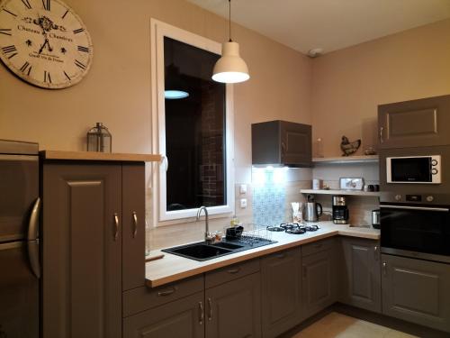 une cuisine avec une grande horloge murale dans l'établissement Les Gîtes du Château de Maltot, à Saint-Ouen-du-Breuil