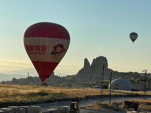 a group of hot air balloons flying over a field at İncebey Konak Cappadocia in Uçhisar