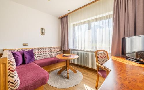 a living room with a purple couch and a tv at Huberhof in Ruhpolding