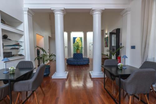 a living room with two tables and chairs and columns at L' Hôtellerie Easy Suites in Palermo