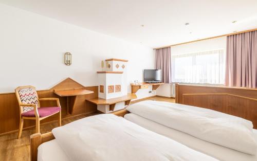 a hotel room with two beds and a table and a chair at Huberhof in Ruhpolding