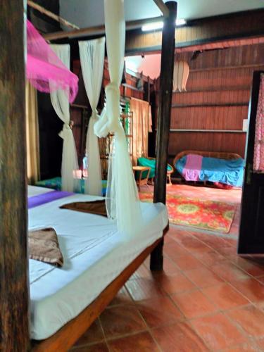 a bedroom with a bed with white sheets and curtains at Jungle House Kep in Kep