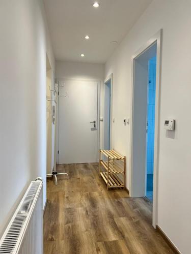 a hallway with white walls and wood floors and a door at Wohnung mit 3 Schlafzimmern nahe Red Bull Ring in Trofaiach