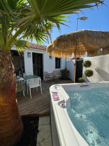 une cour arrière avec un bain à remous et un patio avec un palmier dans l'établissement Charmante maisonnette à Angoulins, à Angoulins-sur-Mer