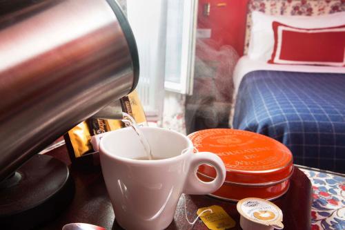 a cup of coffee on a table next to a bed at Le Relais Montmartre in Paris