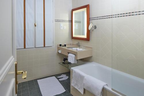 a bathroom with a sink and a tub and a mirror at Le Relais Montmartre in Paris
