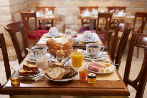 a wooden table with breakfast foods and drinks on it at Le Relais Montmartre in Paris