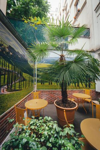 a room with tables and a potted plant and a mural at Le Relais Montmartre in Paris