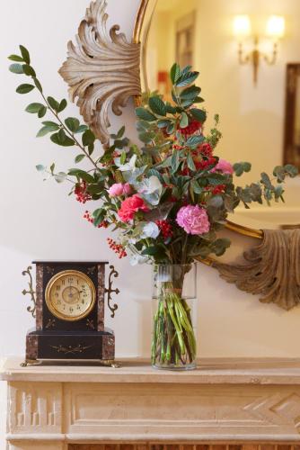a vase with flowers on a table in front of a mirror at Le Relais Montmartre in Paris