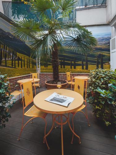 a table and chairs on a patio with a palm tree at Le Relais Montmartre in Paris