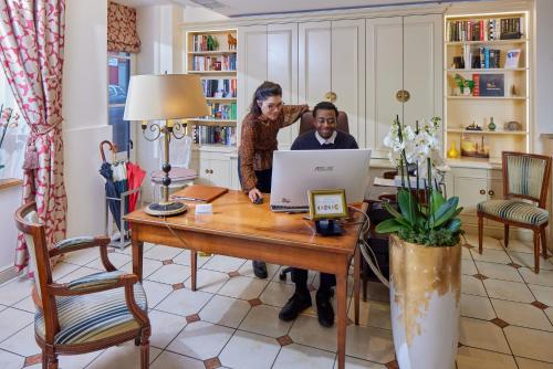 a woman and man standing at a table with a laptop at Le Relais Montmartre in Paris