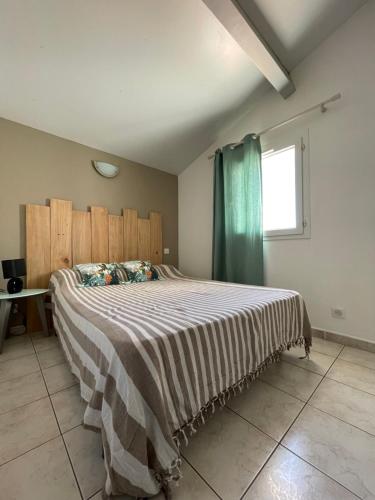 - une chambre avec un grand lit et une couverture rayée dans l'établissement Residence du Grand Large, à Marseillan