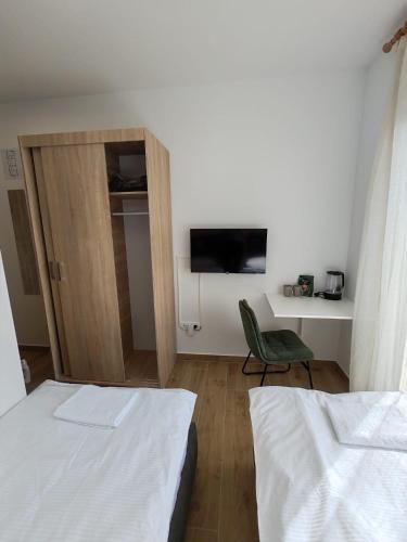 a bedroom with two beds and a chair and a tv at Adriatica in Zadar