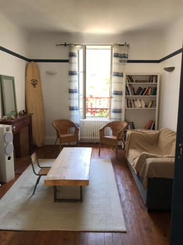 a living room with a table and a surfboard at Appartement Terrasse Plage in Biarritz