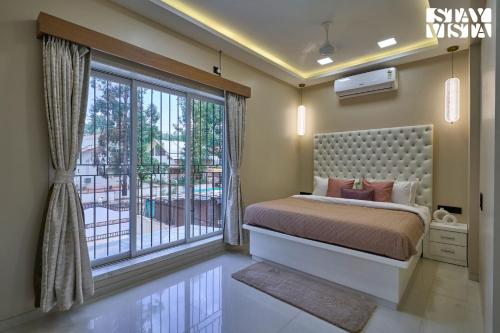 a bedroom with a bed and a large window at Elegant Escapes with Swimming Pool, Lawn & Bonfire at Panchgani by StayVista in Panchgani