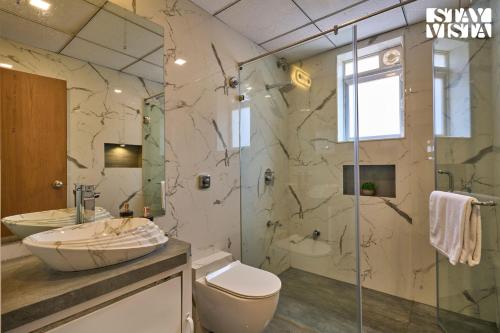 a bathroom with a toilet and a sink and a shower at Elegant Escapes with Swimming Pool, Lawn & Bonfire at Panchgani by StayVista in Panchgani