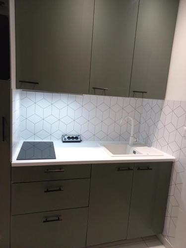 - une cuisine blanche avec un évier et un miroir dans l'établissement Maisonnette entière, à Ivry-sur-Seine