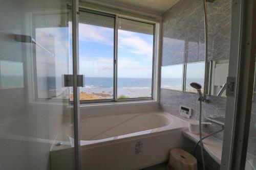 a bathroom with a bath tub and a window at CHLOROBIANCO amami in Amami