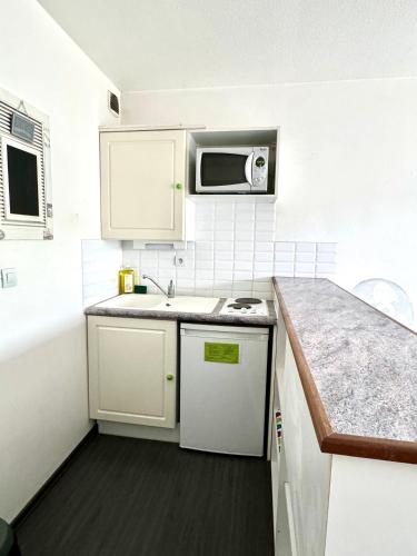 une petite cuisine avec un évier et un micro-ondes dans l'établissement Appartement La Rochelle, à La Rochelle