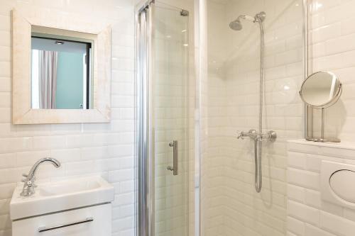 une salle de bain blanche avec une douche et un lavabo dans l'établissement Pick A Flat's Apartment in Saint-Germain des Près - Rue Paul Louis Courier, à Paris