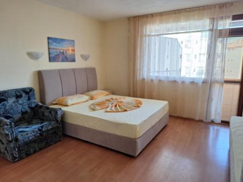 a bedroom with a bed and a chair in it at Primorski Briz Guest House in Primorsko