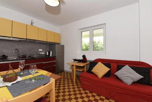 a living room with a red couch and a kitchen at Apartment Happy place in Baćina