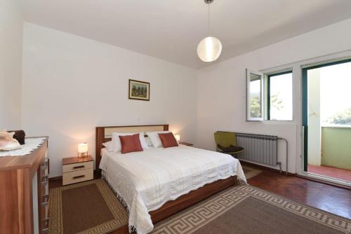 a white bedroom with a bed and a window at Apartment Happy place in Baćina