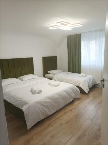 two beds in a room with white walls and wooden floors at Casa Jisa in Turda