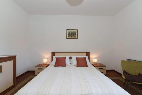 a bedroom with a large white bed with two lamps at Apartment Happy place in Baćina
