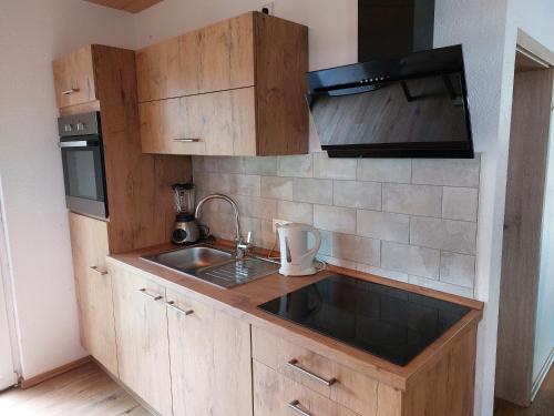 a kitchen with wooden cabinets and a sink at Ferienwohnung im Fehnland 25197 in Bunde