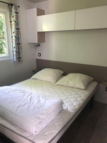 duże łóżko z białą pościelą i oknem w obiekcie mobil-home 4/6 pers w mieście Pont-Aven