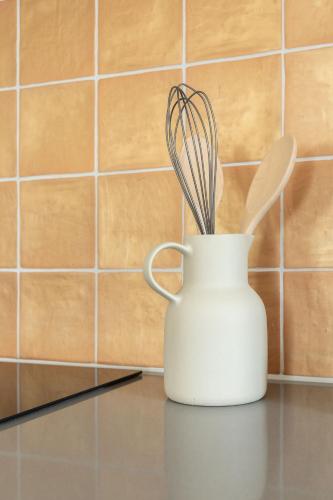 a white vase with some utensils in it at Gezellig appartement in Burum