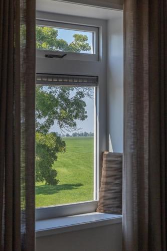 a window with a view of a green field at Gezellig appartement in Burum