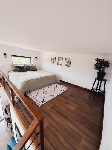 une chambre blanche avec un lit et un parquet dans l'établissement Cozy Tiny House plus SPA - à Pereille d'en Haut, à Péreille