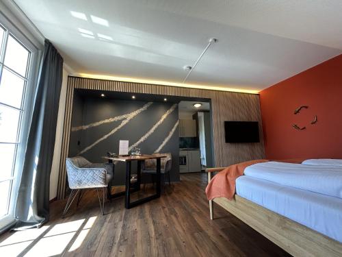 a bedroom with a bed and a desk and a television at Balkon-Studio im Hotel Reindahls in Wilkendorf