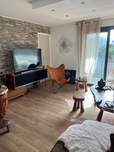 un salon avec une télévision à écran plat sur un mur en briques dans l'établissement Charmant f3 vu Mer, à Ajaccio