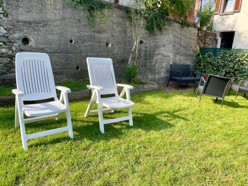 two white chairs sitting in the grass in a yard at I Tre Fratelli in Vignone
