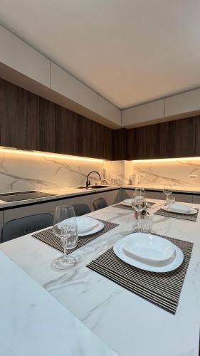 a kitchen with a table with plates and wine glasses at Erlaiden Apartment in Shkodër