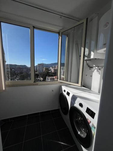 a washing machine in a bathroom with two windows at Erlaiden Apartment in Shkodër