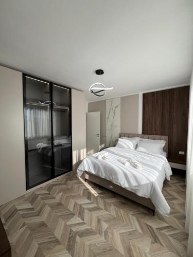 a bedroom with a white bed and a wooden floor at Erlaiden Apartment in Shkodër