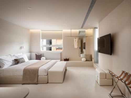a white bedroom with a large bed and a tv at Lore Hotel in Taipei