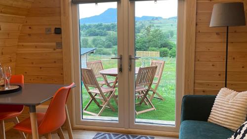 a room with a patio door with a table and chairs at MTB Jumps View Pod in Trawsfynydd